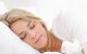 mujer rubia durmiendo sobre una cama con sábanas blancas