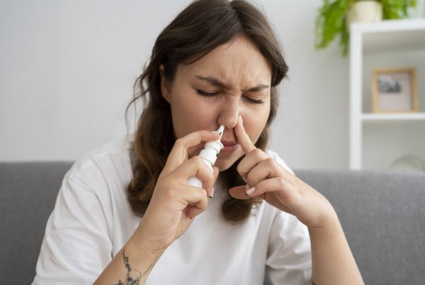 mUJER JÓVEN UTILIZANDO UN SPRY NASAL DE SOLUCIÓN MARINA