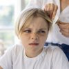 Madre quitando piojos a su hija que está molesta