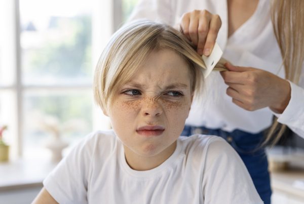 Madre quitando piojos a su hija que está molesta