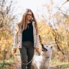 Mujer paseando al perro en un paisaje otoñal